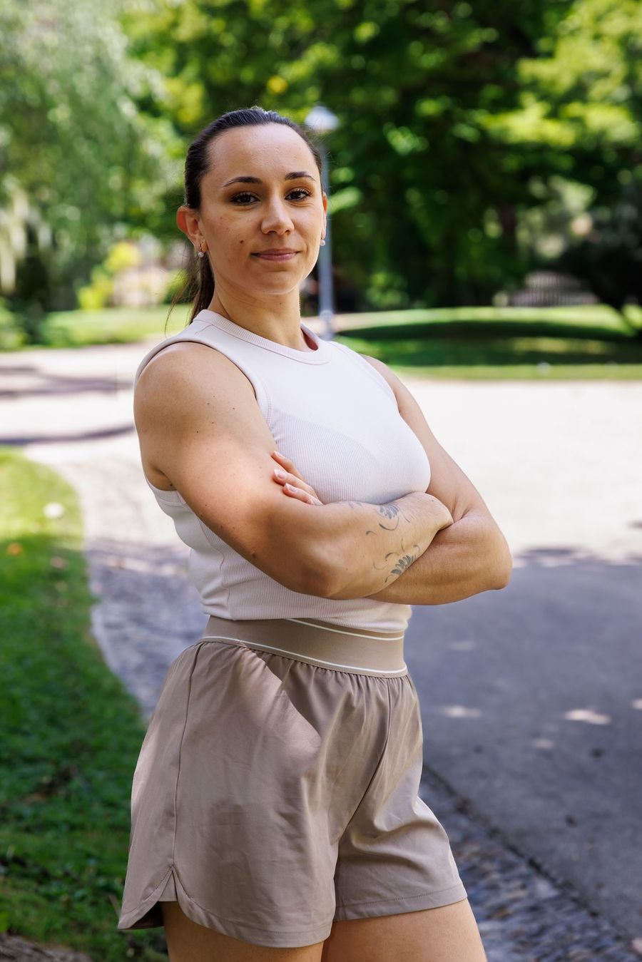 Sarah Granier, bras croisés, dans un parc