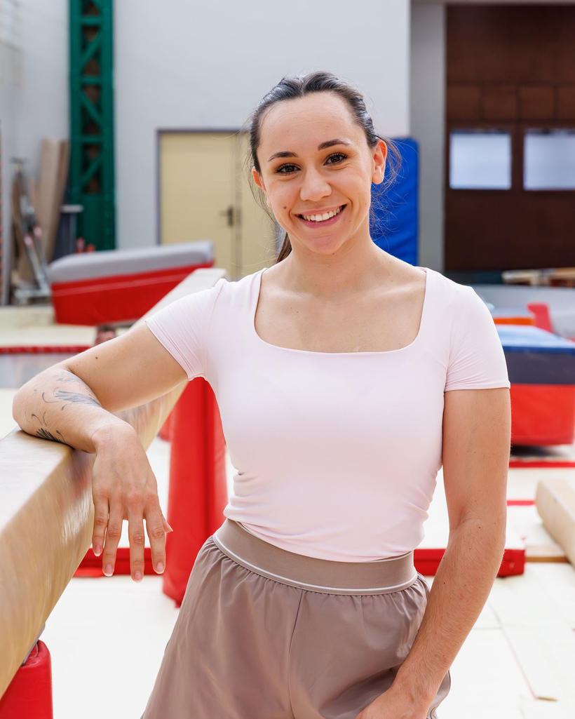 Sarah Granier dans une salle de gymnastique, appuyée sur une poutre